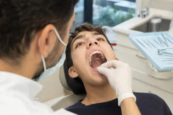 אורתודנט מוסב את מפתח ההרחבה בתוך התקן על החך של מטופל מתבגר במהלך כיוונון מבוקר.