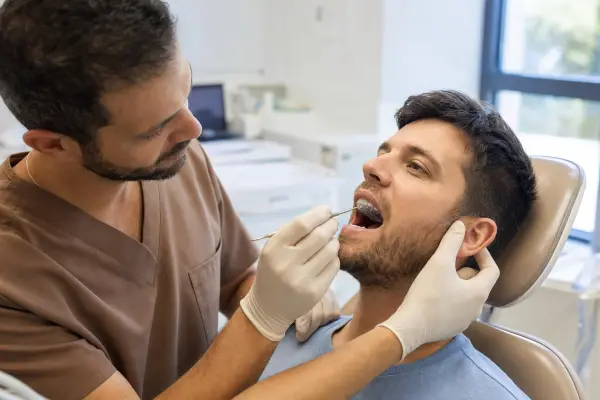 רופא שיניים מתקין ומתאים ספלינט אוקלוזלי קשיח בפה של מטופל במרפאה מודרנית.